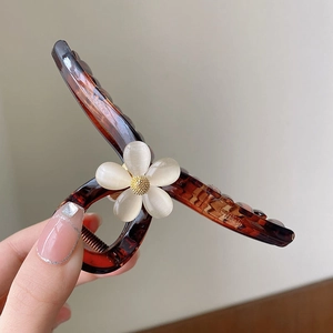 Detail of large tortoiseshell hair claw clip with white pearlescent flower ornament