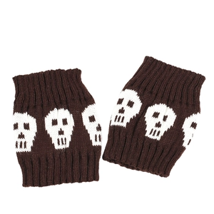 Close-up of knitted brown leg warmers with white skull pattern in soft wool blend fabric