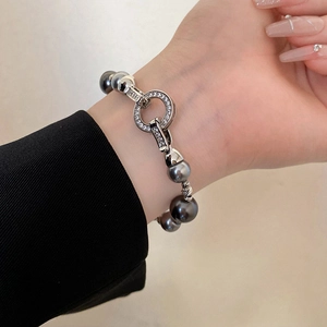 Dettaglio di un bracciale di lusso con perle grigie e chiusura ad anello con strass brillanti