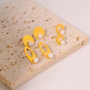 Three pairs of vintage pearl earrings in gold finish on a natural stone base