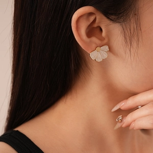 Close-up of elegant petal shaped earrings with gold edges worn by a model