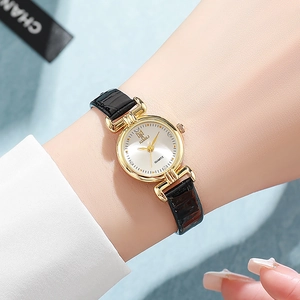 Close-up of elegant women's quartz watch with gold case and leather strap on wrist