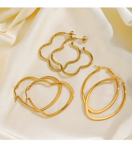 Close-up of gold stainless steel heart and flower earring set on beige silk fabric