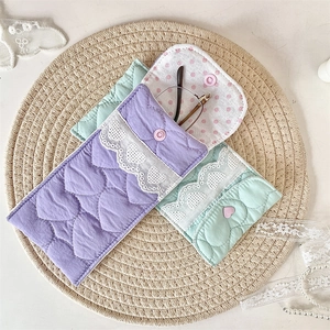 Close-up of quilted heart pattern and pink button closure on soft fabric eyewear pouch