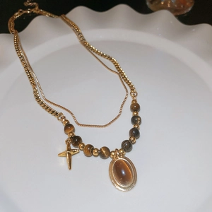 Detail of vintage double-layer gold necklace with cross and tiger eye stone pendants