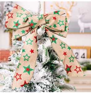 Close-up of rustic star print linen Christmas bow ornament hanging on a snowy cedar tree