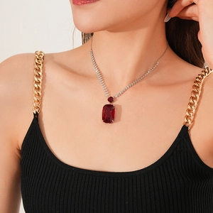 Close-up of a large square red gemstone pendant on a silver chain worn by a model