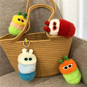 Detail van een kleurrijke pluche rups sleutelhanger met bril op een geweven tas