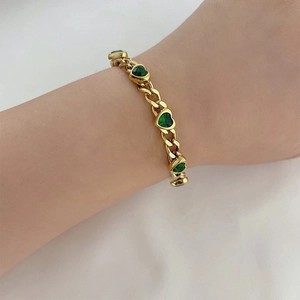 Gold Cuban chain bracelet featuring heart-shaped green zircon stones worn on wrist