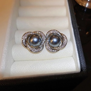 Gros plan de boucles d'oreilles perles gris foncé avec spirale argentée et zircons