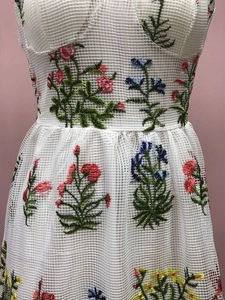 Detailansicht bunter Blumenstickerei auf weißem Netzstoff-Kleid mit feiner Textur