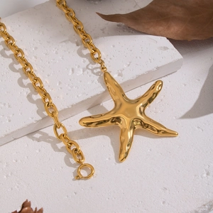 Golden starfish pendant necklace with heavy chain links on white textured background
