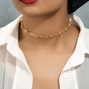 Hip hop punk style golden thorn wire necklace worn by a model against a grey wall