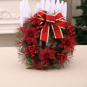 Christmas wreath with red poinsettias, golden berries, and a festive bow for home door decoration
