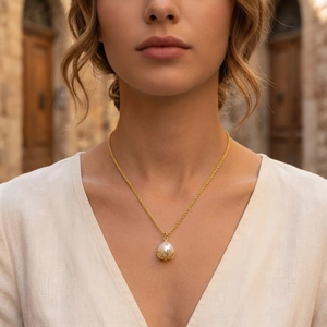 Close-up of a delicate gold twist chain necklace with a pearl pendant on a female model