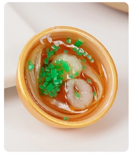 Close-up of miniature gold bowl with realistic shrimp noodles and resin broth