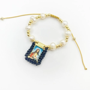 Detailed view of handmade religious bracelet with natural pearls and Jesus pendant