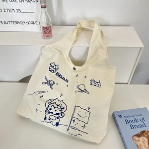 Off-white printed canvas tote bag with cartoon space cow illustration and metal snap closure