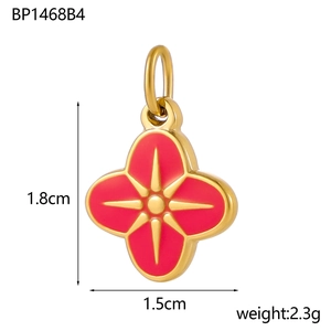 Detail view of a gold four-leaf clover pendant with red enamel and size annotations