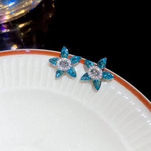 Macro shot of a five-petal flower earring with blue marquise zircon and silver finish