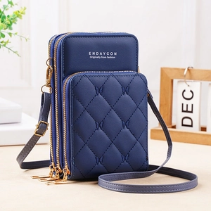 Close-up of triple gold zippers and quilted diamond texture on a navy crossbody phone bag
