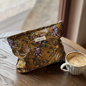 Detail of vintage caramel jacquard makeup bag with floral patterns on wooden table
