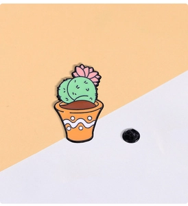 Detail of cartoon cactus enamel pin with pink flower and orange pot on a split background
