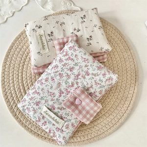 Floral and checkered fabric book covers with heart button closure on a straw mat