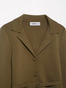 Détail du blazer en maille vert olive avec texture du tissu et ceinture à boucle métal