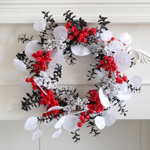 Weihnachtskranz mit roten Beeren und silbernen Akzenten an einem weißen Kaminsims