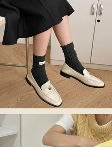 Close-up of black cotton socks with ruffle edges and white labels worn with loafers
