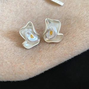 Macro detail of creamy white irregular flower earrings with pearl and gold leaf inlay