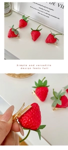 Detailed macro view showing realistic strawberry hair clips with golden metal duckbill base
