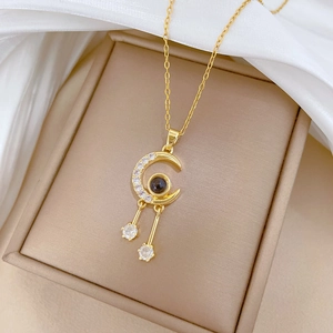Close-up of gold moon and star necklace with shimmering cubic zirconia and projection stone