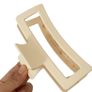 Matte beige rectangular hair claw clip for women held in hand for size visualization