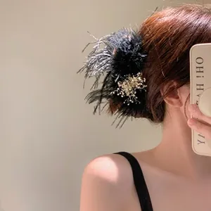Detail showing elegant black feather hair claw clip worn on hair with aesthetic texture