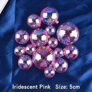 Close-up of 5cm iridescent pink decorative cake topper balls on blue satin fabric