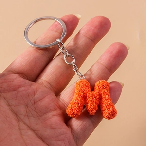 Detail of orange resin letter M keychain featuring intricate 3D rose flower textures