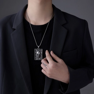Vue détaillée du pendentif rectangulaire à tête de mort argentée porté sur un costume