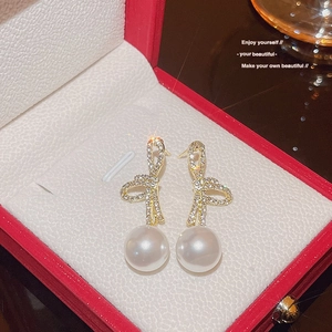 Close-up of elegant bow earrings with sparkling rhinestones and pearls in a jewelry box