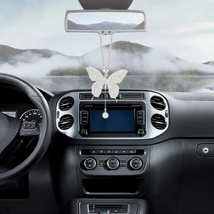 Macro detail of diamond-encrusted silver butterfly car charm hanging from rearview mirror