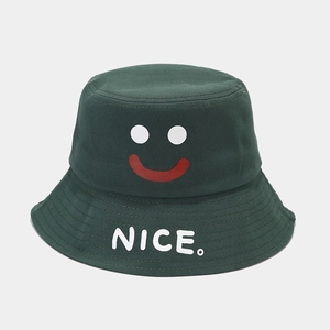 Detail of a dark green bucket hat featuring a smiley face and white NICE text print