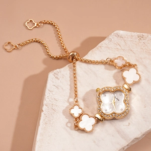 Close-up of golden clover-shaped quartz watch with rhinestones and pull-out bracelet