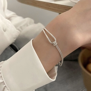 Polished silver knot chain bracelet with U-ring buckle shown on a female model wrist