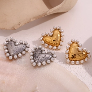 Macro detail of heart-shaped pearl earrings in gold and silver with water droplets