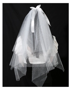 Close-up of white mesh bridal veil featuring a minimalist satin bow on a dark background