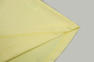 Detail shot of high-quality flat stitching and seam density on a bright yellow knit dress