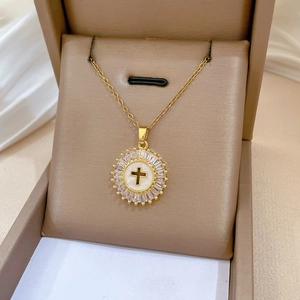 Dettaglio della collana con ciondolo a croce dorata e zirconi cubici scintillanti