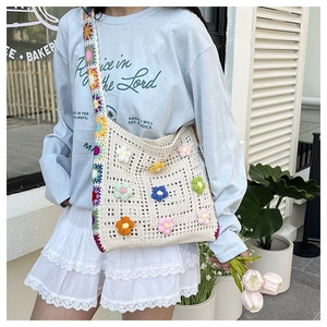 Detail of handmade crochet shoulder bag featuring 3D floral accents and woven strap
