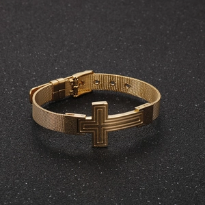 Detail of adjustable gold mesh bracelet featuring a polished cross and watch strap buckle